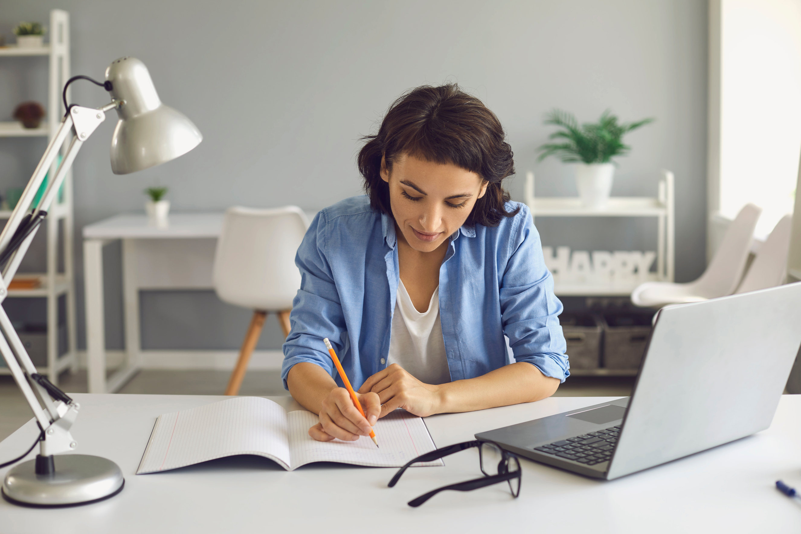 Young Woman Student Making Notes during Online Lesson